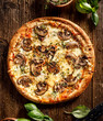 Mushroom pizza with addition mozzarella cheese and herbs on a wooden table, top view