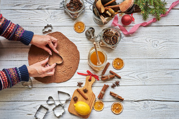 Wall Mural - Female hands  pressing the dough with cutter to make cute  gingerbread . woman  making sweet xmas cookies in her small workshop indoors.