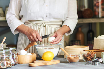 Wall Mural - Woman breaking the egg in preparation of the dough. Making Christmas gingerbread.