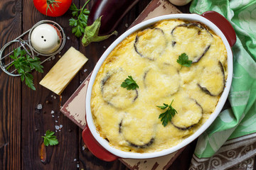 Eggplant casserole with beshamel (moussaka) - a traditional Greek dish on the kitchen wooden background. Top view flat lay background.