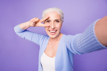 Poster - Elderly lady makes selfie on the camera of a smartphone making v