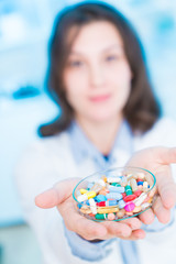 Poster - young woman doctor smiling and holding one pill over blue background