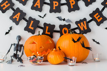 Holidays And Decoration Concept - Jack-o-lantern Or Carved Pumpkins With Candies And Happy Halloween Garland On White Background
