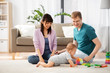 © Syda Productions - family, parenthood and people concept - happy mother, father and baby boy playing toy blocks at home