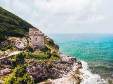 Beautiful Scene, Old Building. Ancient Defense Tower On Mountain In The Mediterranean Sea. Paola Tower Is Placed On Circeo Promontory Of Sabaudia, Italy. View From Drone, Aerial.