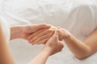 © DragonImages - Anonymous massage therapist rubbing palm of unrecognizable woman during spa session in salon