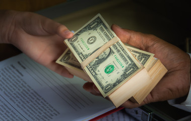 Businessmen use money to bribe other people in exchange for signing contracts, with blurred soft background to Dark business concept