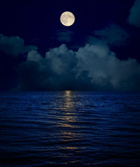 full moon over clouds and dark water with reflections