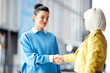 © pressmaster - Two young attractive women shaking hands and standing in big office hall