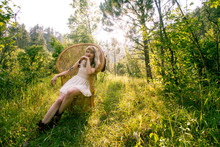 Caucasian Woman In Forest Alone In White Dress With Wicker Chair