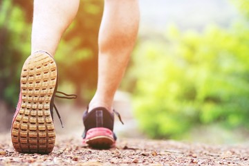 Wall Mural - Sportsman foot runner trail running outdoors. close up on shoe behind of a man running fitness jogging workout uphill in autumn trail of nature and stones. exercise healthy lifestyle and sport concept