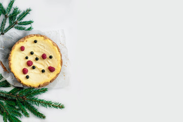 Classic Festive Christmas cheesecake on a light wooden background with Christmas tree. Christmas white chocolate cake with mascarpone. Traditional winter cake recipe. Сelebration background. 