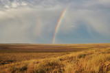Fototapeta Tęcza - Rainbow in sky among  landscape over the boundless savannah, summer nature background, blue sky with clouds. The rainbow crosses the sky over desert. The concept of exotic tourism.