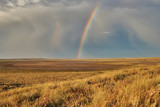 Fototapeta Tęcza - Rainbow in sky among  landscape over the boundless savannah, summer nature background, blue sky with clouds. The rainbow crosses the sky over desert. The concept of exotic tourism.