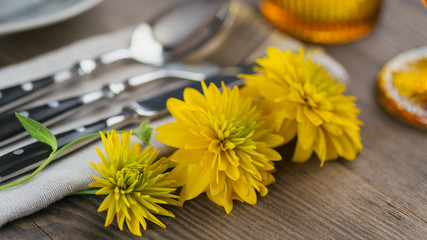 Wall Mural - Rustic table setting with linen napkin, cutlery, ceramic plates, yellow glasses and yellow flowers