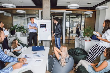 Wall Mural - corporate meeting of creative entrepreneurs in the office, two men speak to colleagues