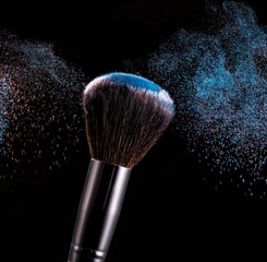 Make up brush with powder splashes on black background