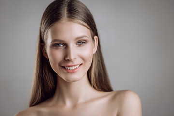 Wall Mural - Portrait of a beautiful young girl with nude make-up in studio on a gray background