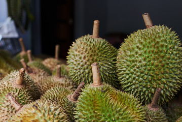 Fresh exotic tropical fruits durian for sale at an outdoor market.  Durian has been arranged on the shelf to be displayed.  King of fruit durian fruits on the market of Thailand.