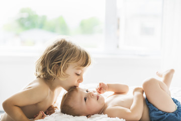 baby in bed with his brother son giving a kiss