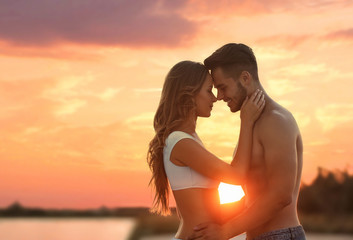 Poster - Happy young couple in beachwear outdoors at sunset