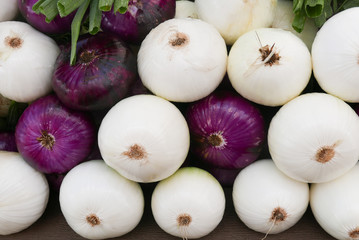 Purple and white onions stacked at the farmers market creating an overall background