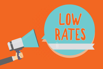 Conceptual hand writing showing Low Rates. Business photo showcasing A cost of an item or service which is usualy at its smallest price Man holding megaphone blue speech bubble orange background.