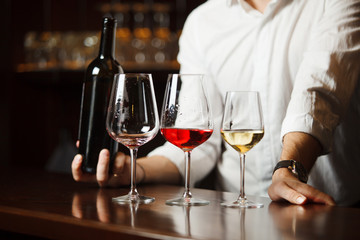 Wall Mural - Wineglasses placed on wooden table and sommelier