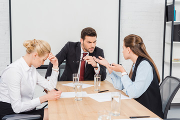 angry boss talking with his female colleagues at modern office