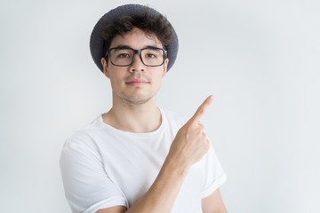 Portrait of serious young Asian man pointing with finger. Vietnamese guy wearing glasses and sunhat advertising something, Promotion concept