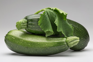 Whole green zucchini and leaves on white background, isolated. Copy space.