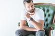 © LIGHTFIELD STUDIOS - brunet handsome man sitting in green armchair, isolated on white