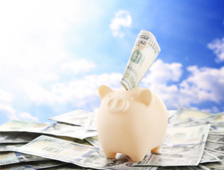 Poster - Piggy bank with money on blue sky background