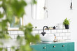 Close-up of blurred leaves with a sink, green cupboard and mirror in the background in the bathroom interior. Real photo