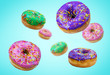 Multiply donuts with violet, pink, green glaze and icing flying on blue background in motion. Advertising illustration.