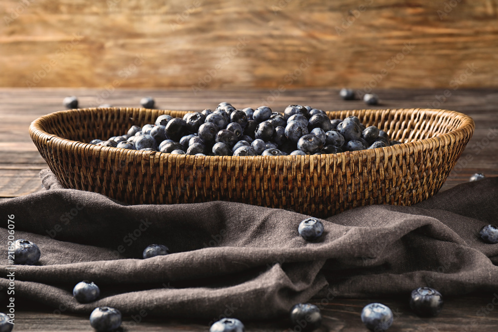 Wicker basket with ripe blueberries on table