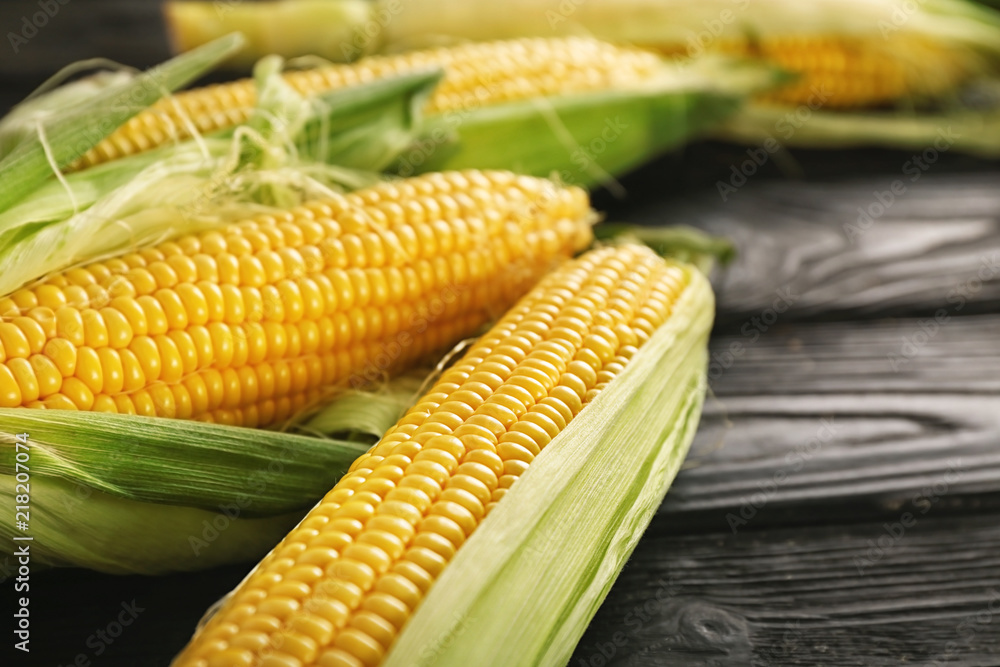 Fresh corn cobs on wooden table, closeup