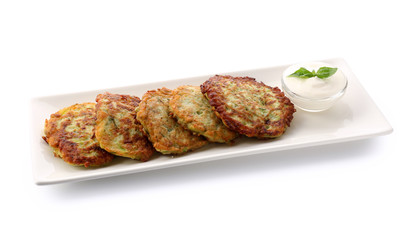 Plate with zucchini pancakes and sauce isolated on white