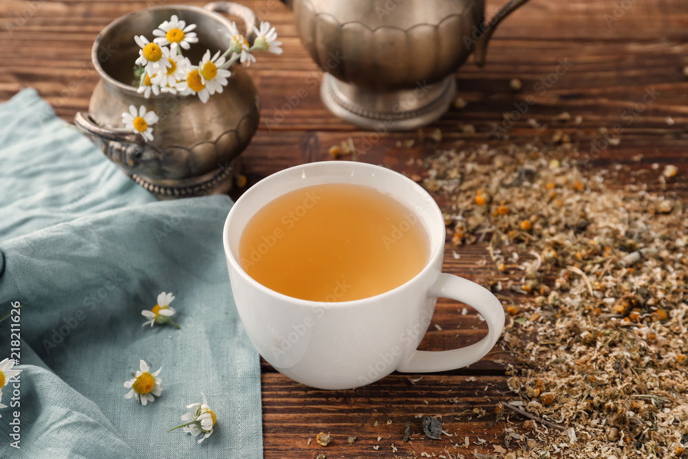Cup of delicious camomile tea on wooden table