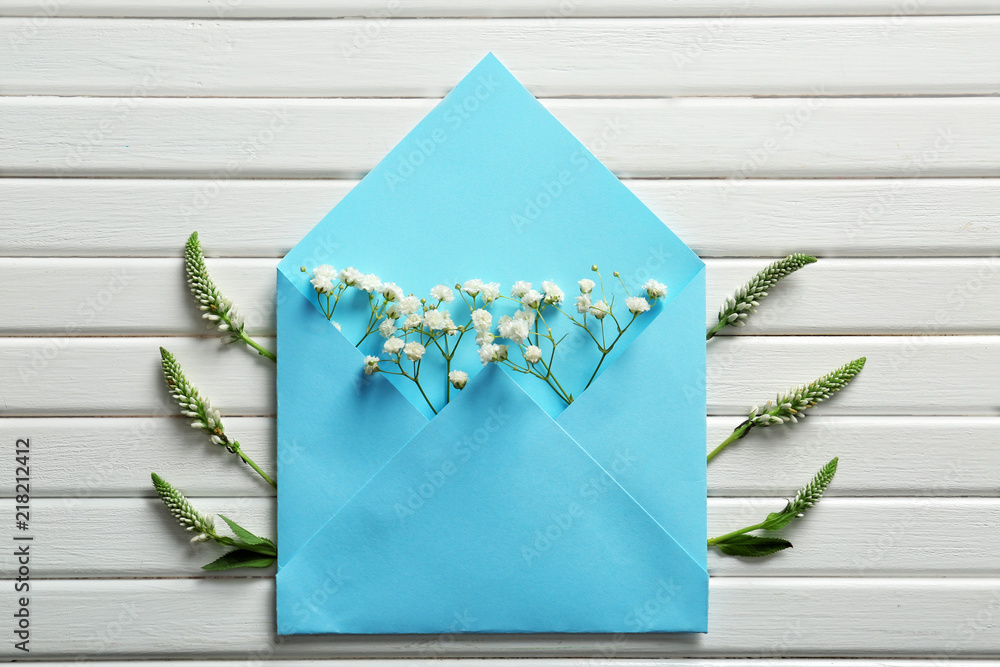 Open mail envelope with flowers on white wooden background