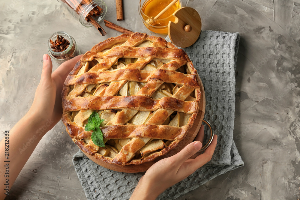 Woman putting delicious apple pie on table