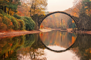  Rakotz Bridge (Rakotzbrucke, Devil's Bridge) in Kromlau, Saxony, Germany. Colorful autumn, reflection of the bridge in the water create a full circle.Unusual and interesting places in Germany.