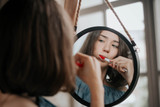 Fototapeta Na ścianę - Beautiful young woman brushing teeth in front of her bathroom mirror.