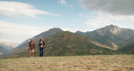 active senior caucasian couple hiking in mountains with backpacks, enjoying their adventure 4k