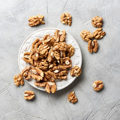 Wall Mural - Walnut kernels on white plate over gray background.