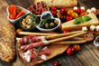 © beats_ - Italian antipasti wine snacks set. Cheese variety, Mediterranean olives, crudo, Prosciutto di Parma, salami and wine in glasses over wooden grunge background.