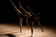 © nagaets - Flexible ballerinas stretch on a dark lighted scene