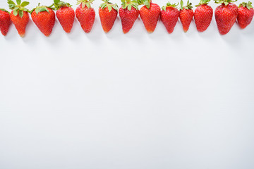 strawberry fruits in a row on white wood table background