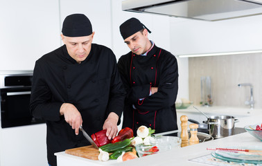 Wall Mural - Men kitchener in uniform are cutting vegetables for salad in the kitchen