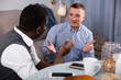 © JackF - Positive male friends using mobile, talking in home interior